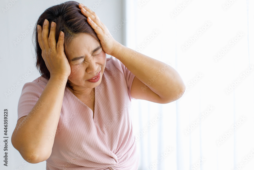 Senior woman using hands to catch and hold her head with pain and suffer warped face from headache with cerebrovascular disease or head stroke Senior woman using hands to catch and hold her head with pain and suffer warped face from headache with cerebrovascular disease or head stroke