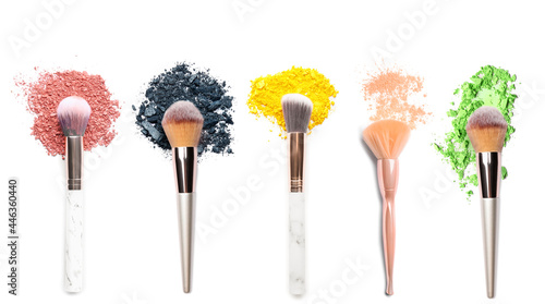 Makeup brushes with crushed eyeshadows on white background