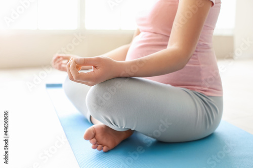 Young pregnant woman practicing yoga in gym, closeup