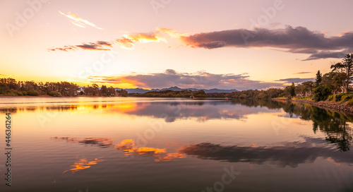 Landscape spectacular golden reflections of the clouds and sunset in the beautiful, calm waters of a broad river in eastern Australia.