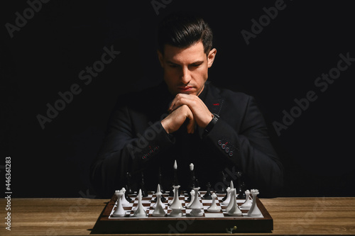 Man playing chess at table on dark background