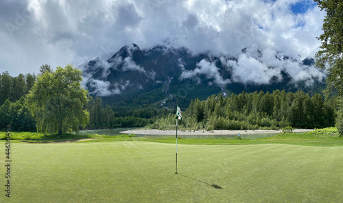 Golf green with flag, river and mountain