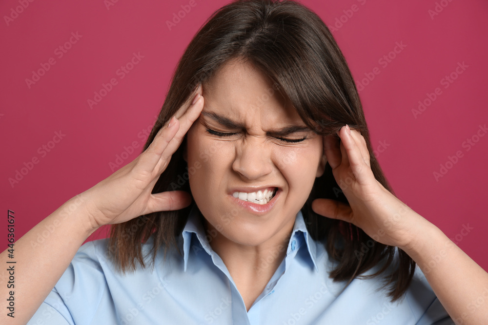 Young woman suffering from migraine on crimson background Young woman suffering from migraine on crimson background