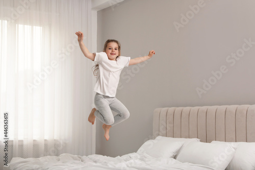 Fototapeta Naklejka Na Ścianę i Meble -  Cute little girl jumping on bed at home
