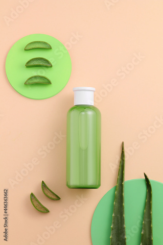 Background with natural cosmetics of aloe vera, fresh leaves of aloe on bright coral and green. Copy space photo
