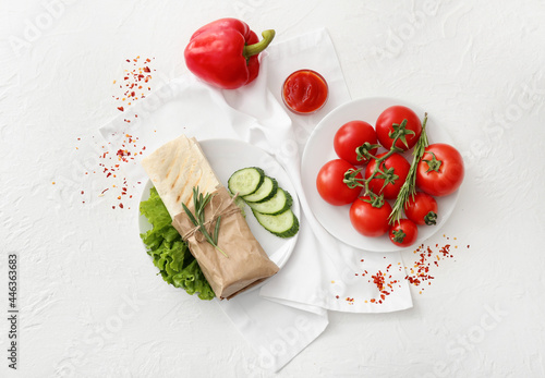 Plate with tasty doner kebab, vegetables and sauce on light background