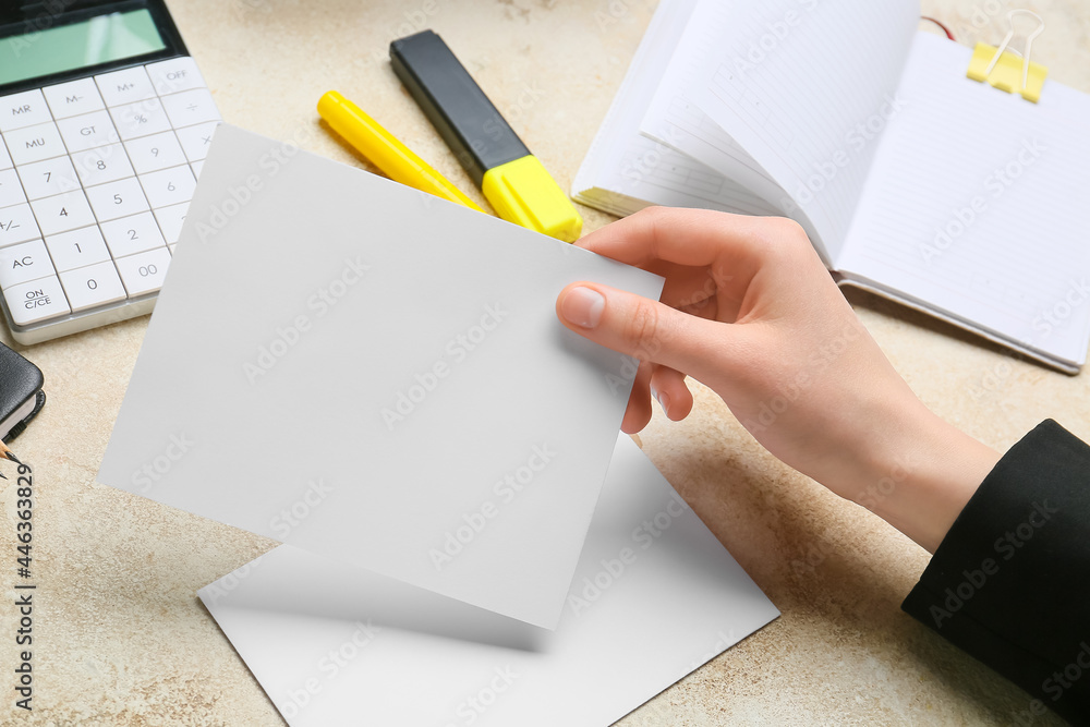 Female hand with blank sheet of paper and stationery on grunge background, closeup Female hand with blank sheet of paper and stationery on grunge background, closeup