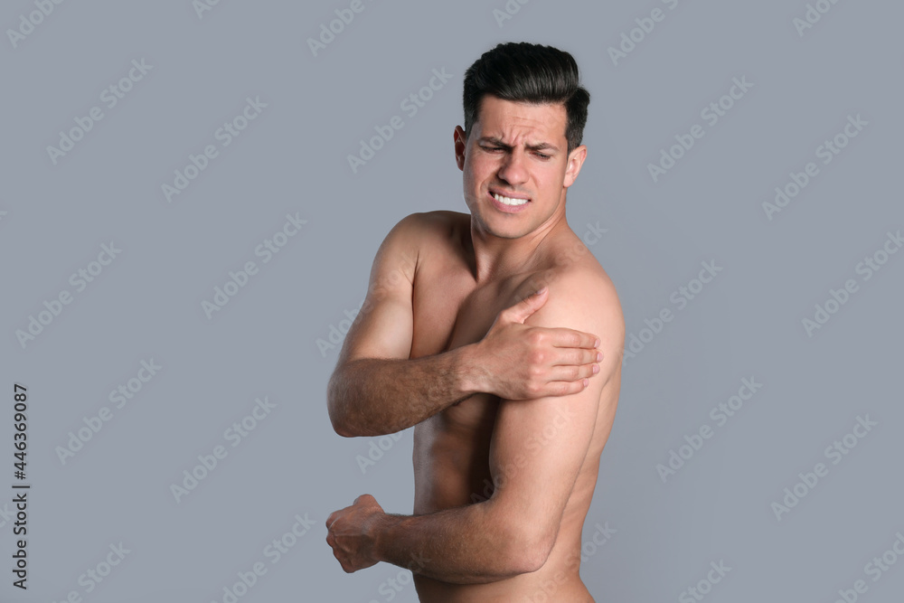Man suffering from shoulder pain on grey background Man suffering from shoulder pain on grey background
