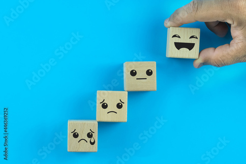 Close up top view customer hand choose a smiley face on the wood cube, Service rating, satisfaction concept.