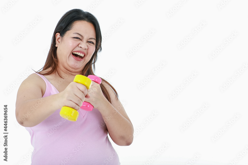 Portrait close up isolated studio shot of Asian happy healthy strong big fat girl stand smile lift pink and yellow dumbbells with two arms in weight lose practice exercise in front white background Portrait close up isolated studio shot of Asian happy healthy strong big fat girl stand smile lift pink and yellow dumbbells with two arms in weight lose practice exercise in front white background