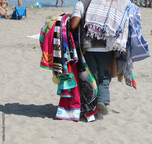 street vendor with beach towels that sells his wares on the beach illegally