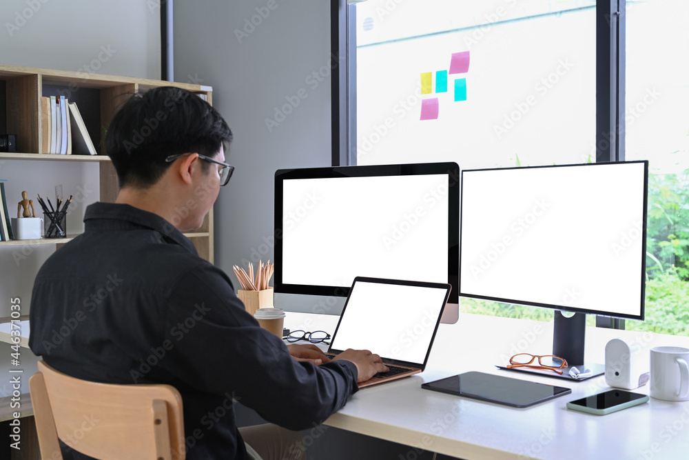 Back view of businessman working with multiple modern gadget at home office. Back view of businessman working with multiple modern gadget at home office.