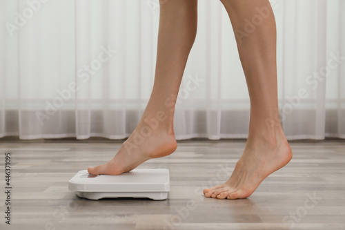 Woman stepping on floor scales indoors, closeup. Weight control © New Africa