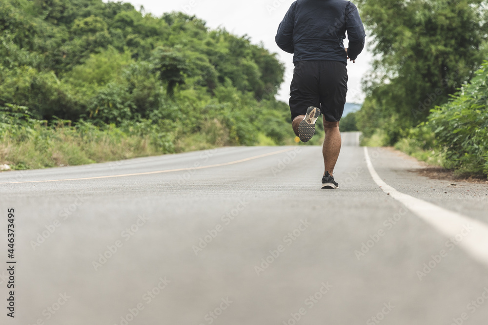 Man wearing sportswear running on the road with mountain background. Young man jogging for exercise in the nature. healthy lifestyle and sports concept.