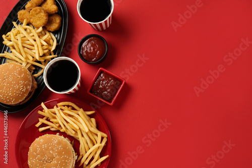 Fototapeta Different fast food on red background, flat lay. Space for text