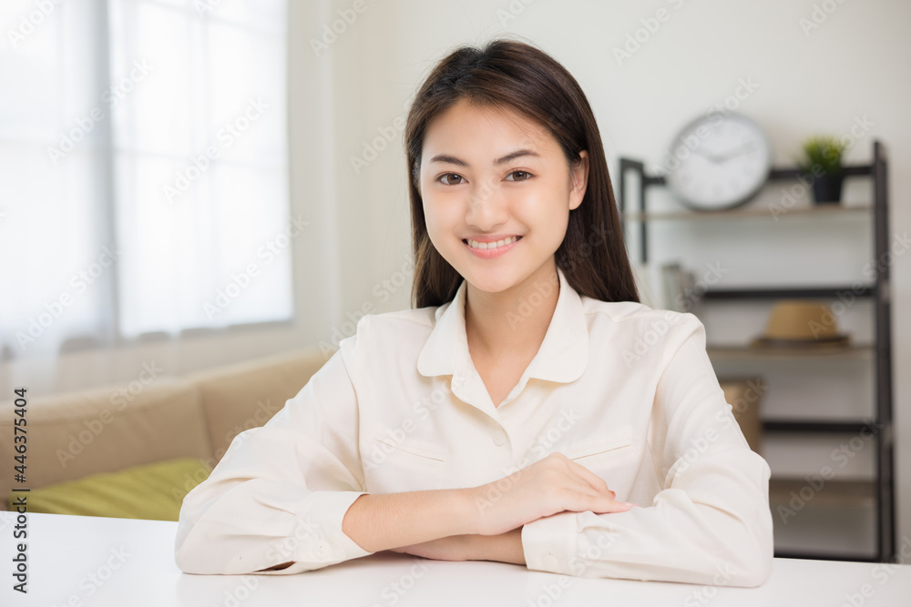 Young asian woman looking at camera video conference online sitting in living room at home. Business Woman looking at screen Meeting on social media live steam. Work, learning from home. Young asian woman looking at camera video conference online sitting in living room at home. Business Woman looking at screen Meeting on social media live steam. Work, learning from home.