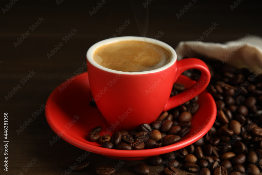 Cup of tasty coffee and beans on wooden table Cup of tasty coffee and beans on wooden table