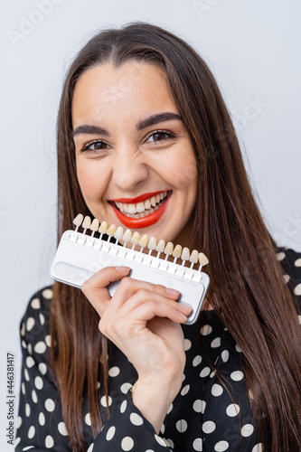 Pretty female with teeth examples. Model young woman holding plastic new teeth.