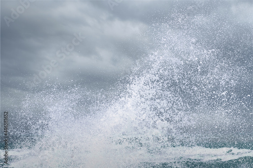 splashing water of sea wave from strom crashing on shore spraying white water foam and bubble in air isolated on stormy cloundy sky background with clipping path