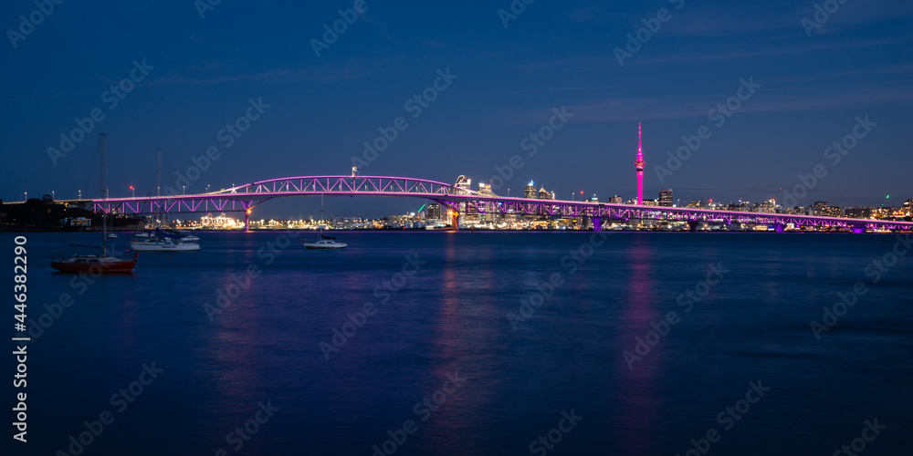 Obraz premium Auckland Sky Tower illuminated in pink and Harbour Bridge in purple