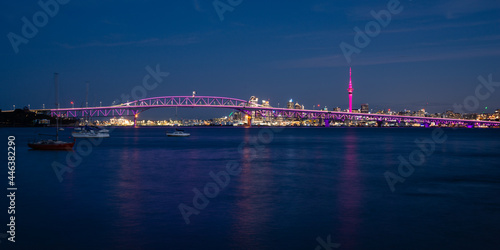 Auckland Sky Tower illuminated in pink and Harbour Bridge in purple