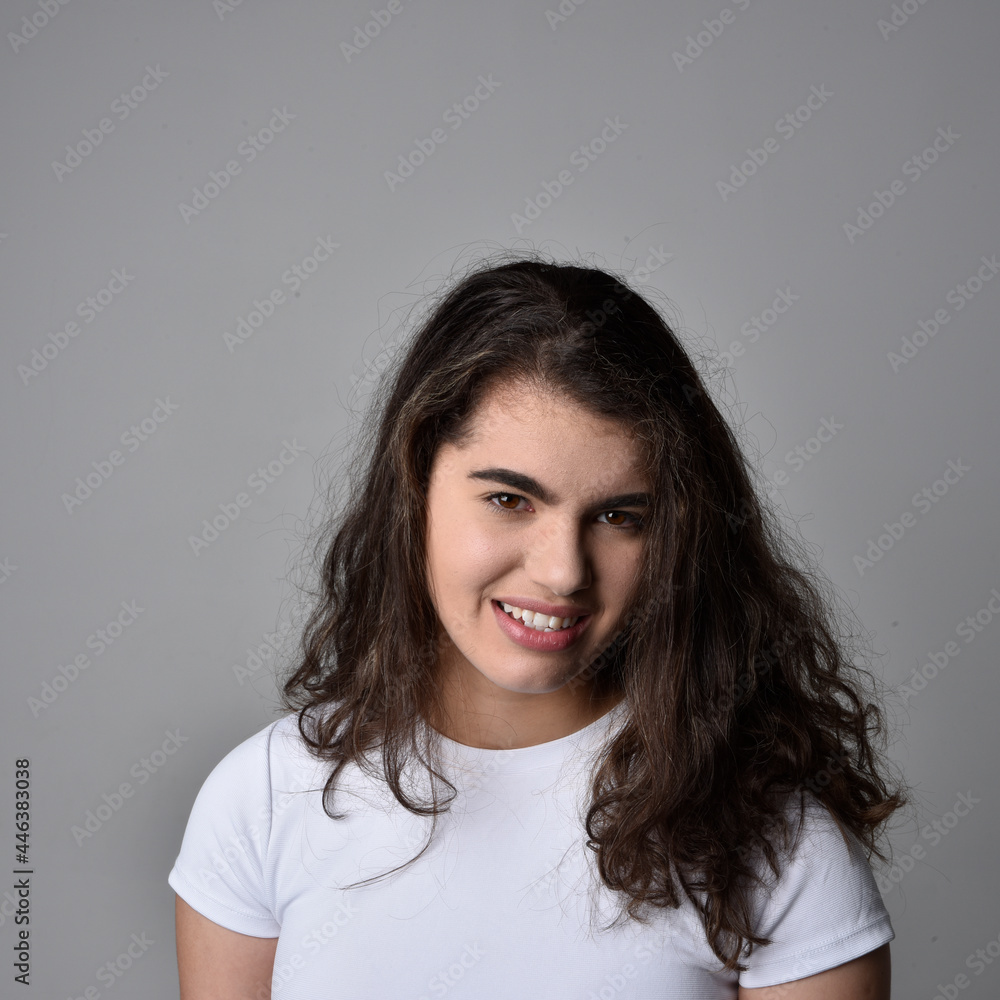 Fototapeta premium Close up portrait of young woman with natural brown hair, over the top facial expressions on light grey studio background.