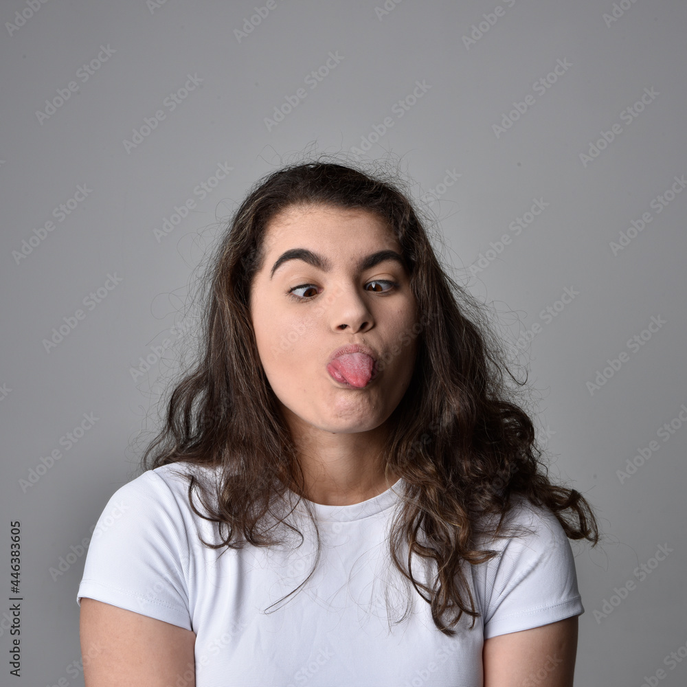 Close up portrait of young woman with natural brown hair, over the top facial expressions on light grey studio background. Close up portrait of young woman with natural brown hair, over the top facial expressions on light grey studio background.