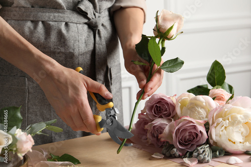 Canvas Print Florist cutting flower stem with pruner at workplace, closeup