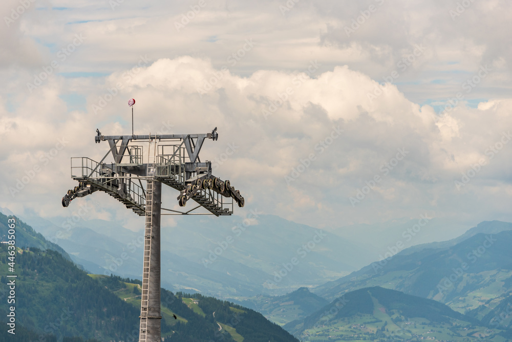 Construction of a new ski lift. Support pole, no steel ropes, standing alone on the slope. Upper ski lift station. Yellow crane at the construction site. In the background mountains panorama