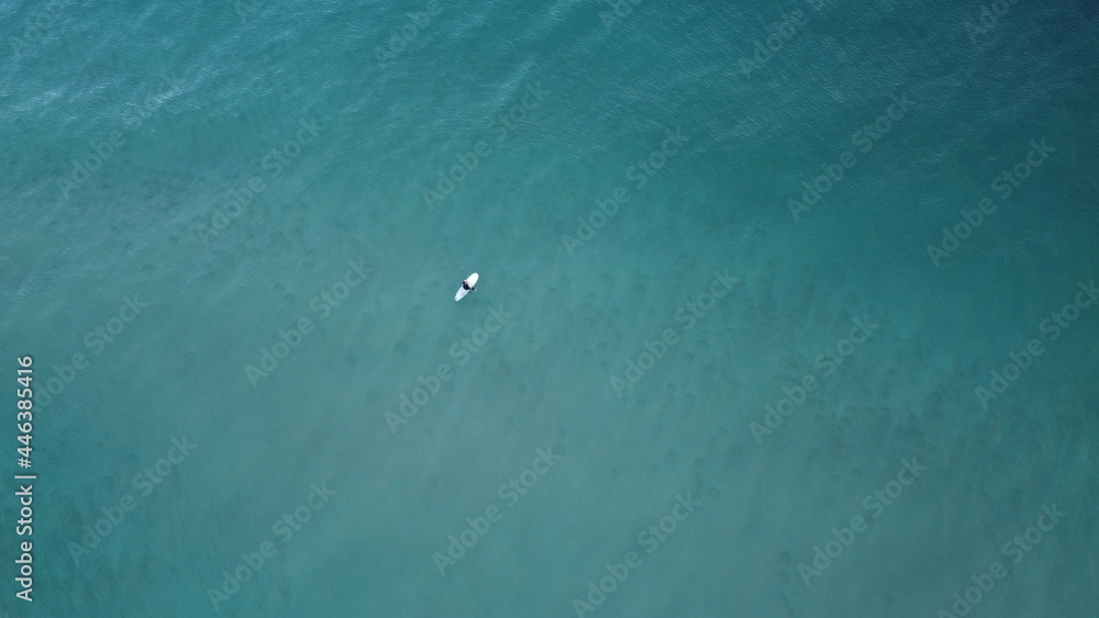 Lone surfer riding out into the sea waiting to catch waves crashing against the beach, summer vibes, coastal Victoria, Great Ocean Road, Australia Lone surfer riding out into the sea waiting to catch waves crashing against the beach, summer vibes, coastal Victoria, Great Ocean Road, Australia