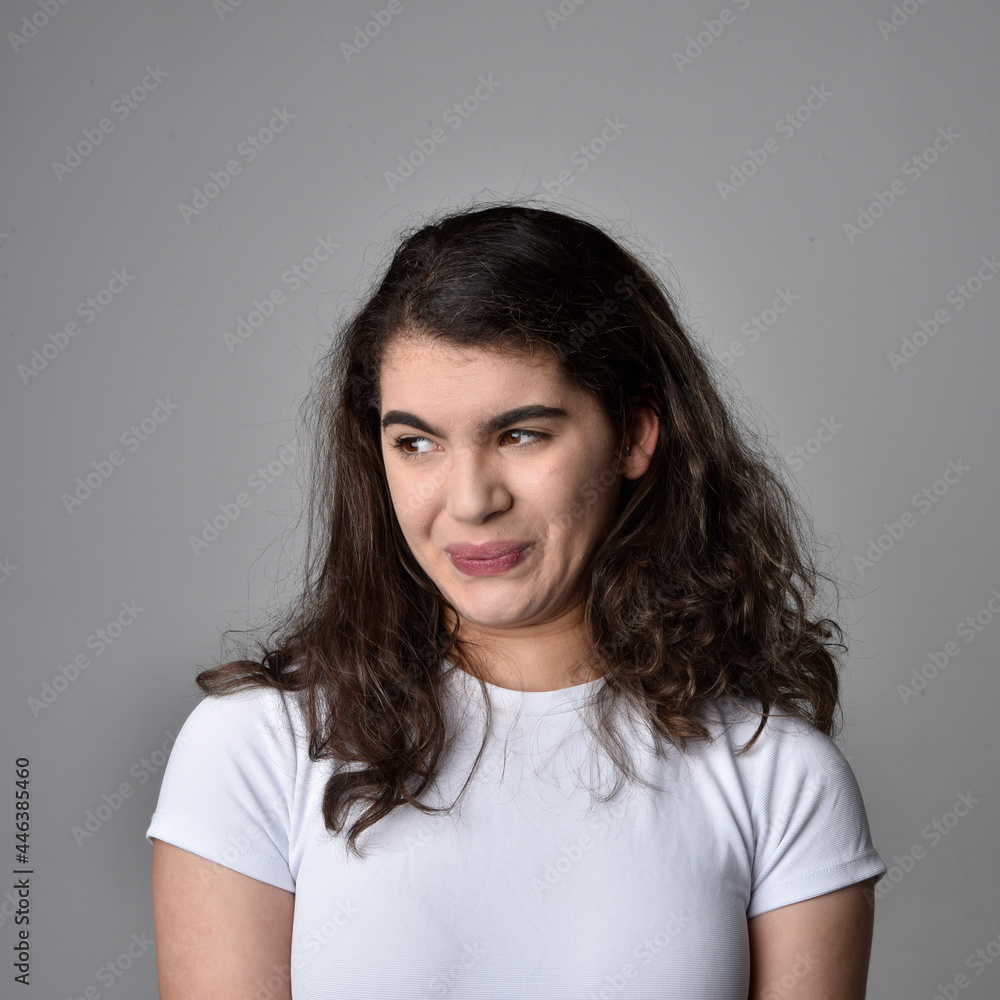 Close up portrait of young woman with natural brown hair, over the top facial expressions on light grey studio background. Close up portrait of young woman with natural brown hair, over the top facial expressions on light grey studio background.