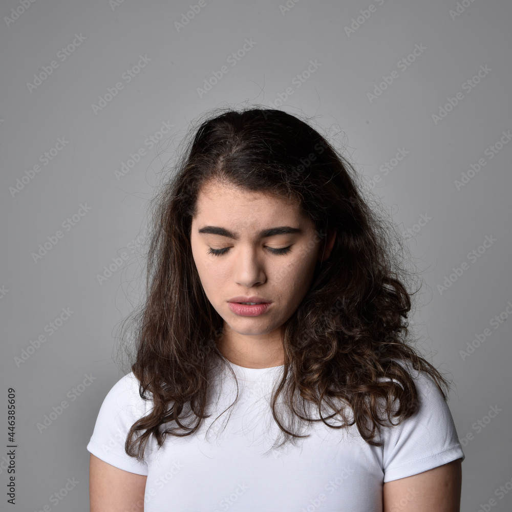 Close up portrait of young woman with natural brown hair, over the top facial expressions on light grey studio background. Close up portrait of young woman with natural brown hair, over the top facial expressions on light grey studio background.