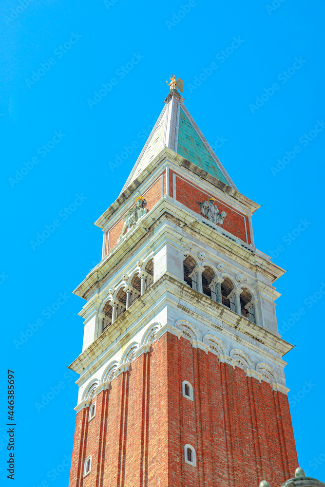 bottom view of San Marco bell tower in San Marco square in Venice with Saint Mark Basilica of Venetian city of Italy. against blue sky. vertical view