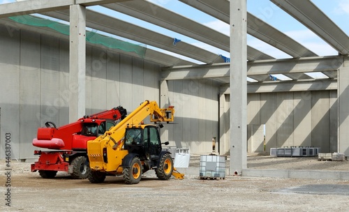 Back of two telescopic handlers inside a concrete block building under construction.