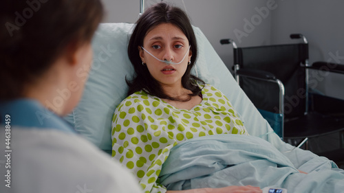 Sick patient lying in bed talking with practitioner doctor explaining disease symptom. Medic specialist writing disease treatment on clipboard discussing sickness expertise working in hospital ward