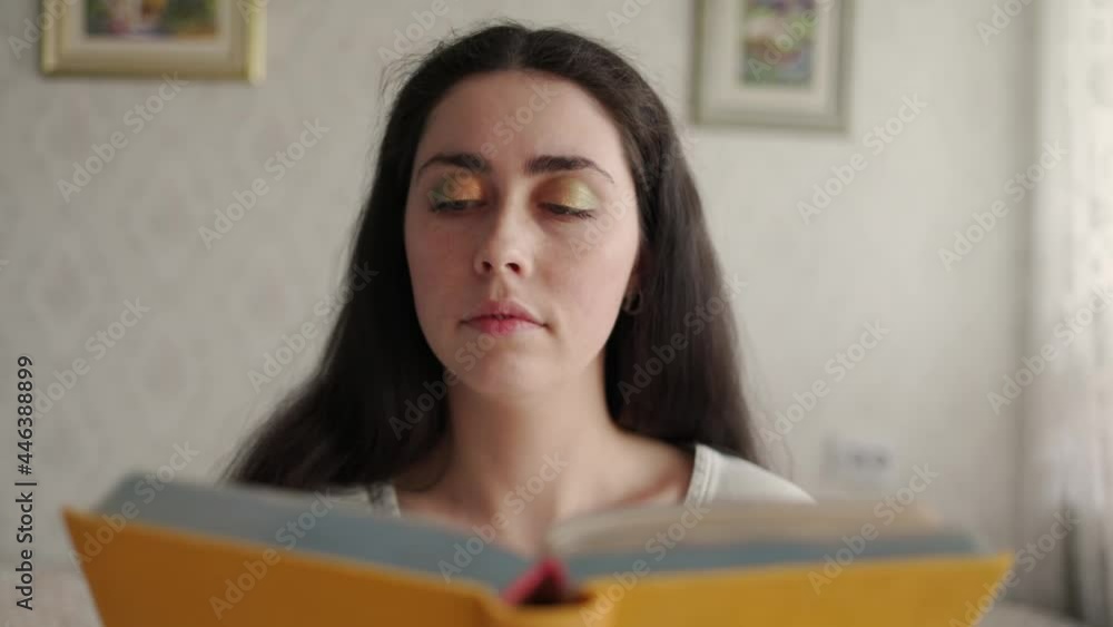 A young woman holds a book in her hands and reads it, then lies down on the bed. The concept of the World Book and Education Day. A young woman holds a book in her hands and reads it, then lies down on the bed. The concept of the World Book and Education Day.