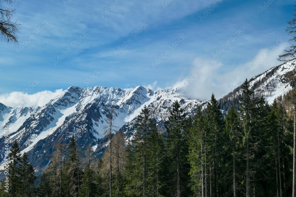 A panoramic view from the top of Alpine peak in Austria. The whole area is shrouded in thick clouds. A few peaks popping out from the clouds. High mountain chains in the back. Carpet from the clouds