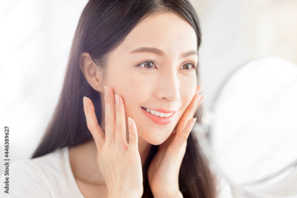 Beautiful Young woman touching face skin and looking in mirror Beautiful Young woman touching face skin and looking in mirror