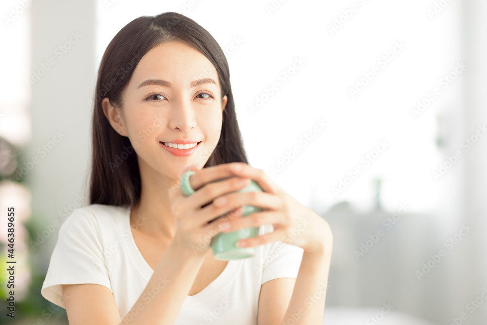 beautiful young woman holding a cup of tea in living room at home