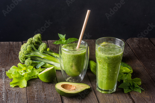 Fresh green smoothie in glass on wooden table, closeup. Detox diet concept: green vegetables on rustic table. Clean eating, alkaline diet, weight loss food concept.