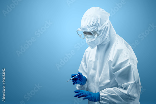 Health worker woman with a protective suit and gloves holding covid 19 vaccines