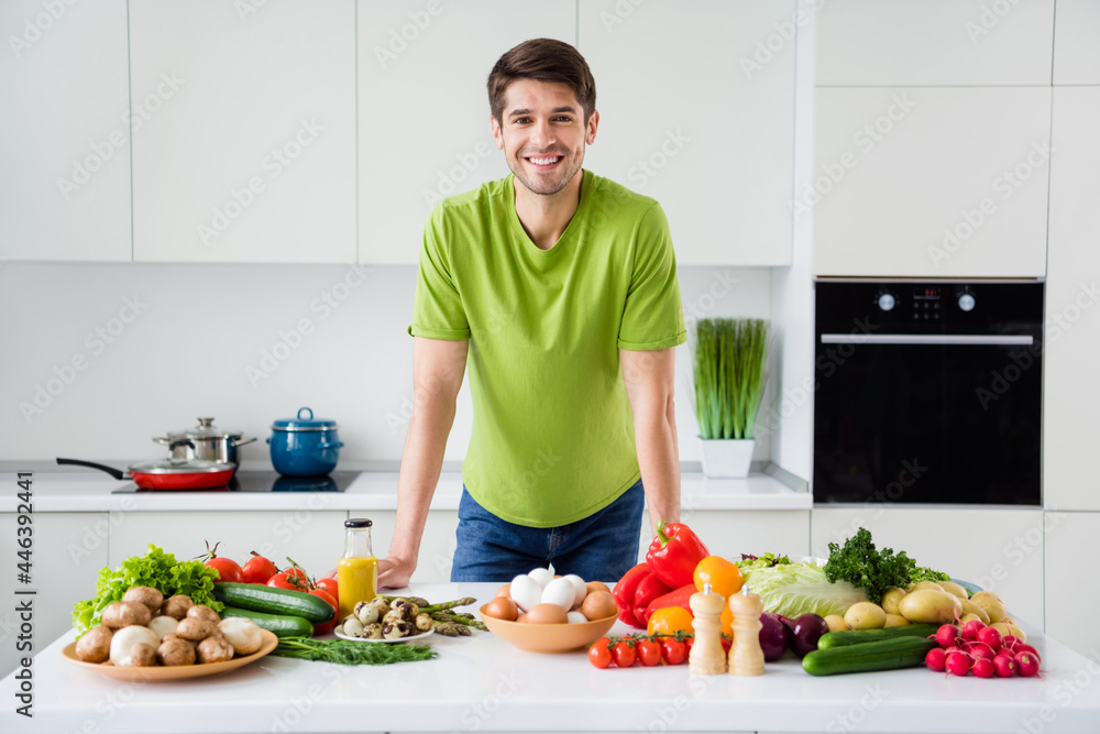Photo portrait young man preparing vegetables salad smiling in kitchen