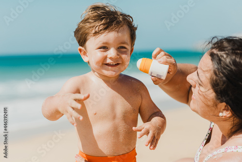 Obraz na płótnie Mother applying sunscreen cream to baby