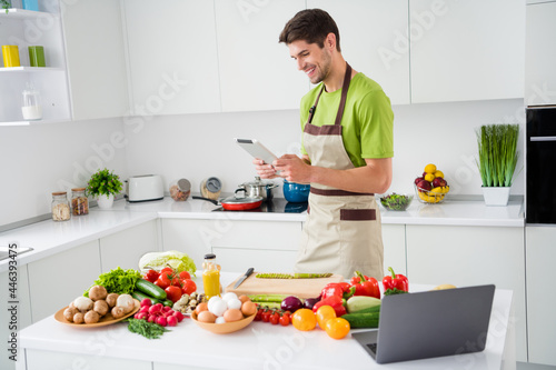 Portrait of attractive cheerful skilled guy cooking delicious salad watching video lesson at home kitchen indoors