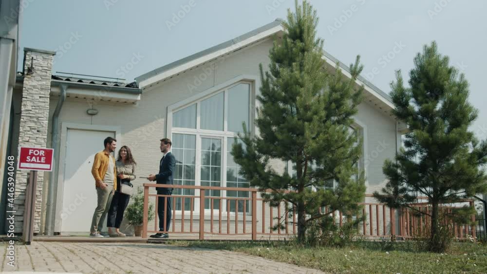 Girl and guy are talking to real estate agent looking at house in suburbs enjoying view discussing sale. Buying and selling property concept. Girl and guy are talking to real estate agent looking at house in suburbs enjoying view discussing sale. Buying and selling property concept.
