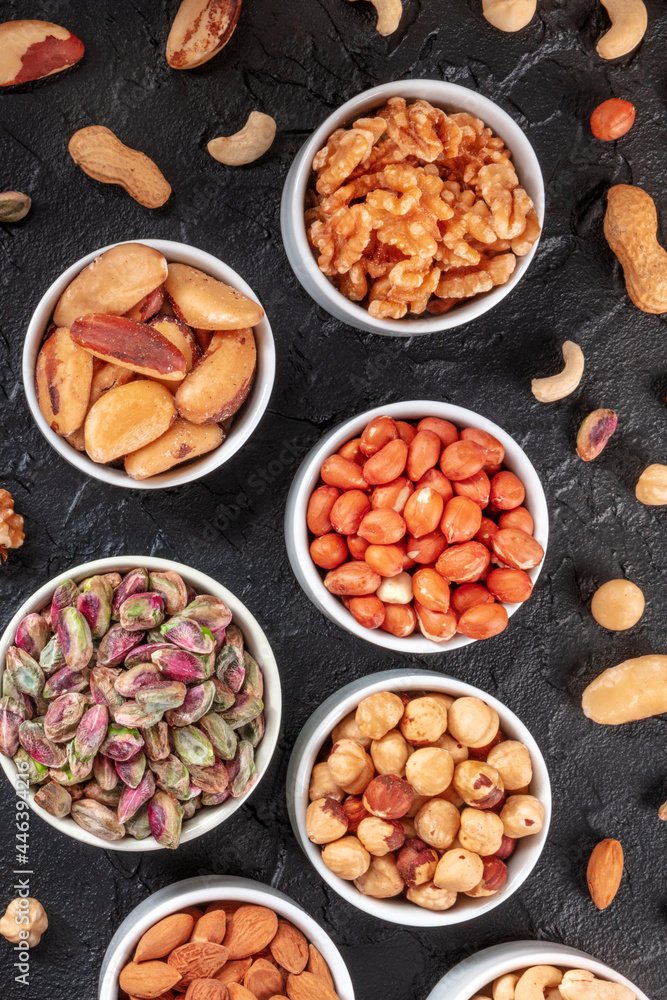 Many different nuts in bowls, shot from the top on a black slate background Many different nuts in bowls, shot from the top on a black slate background