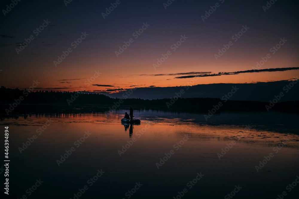 The silhouette of a father and son fishing on a beautiful lake at sunset.