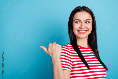 Photo of young sweet smiling cheerful girl look copyspace advertising product isolated on blue color background