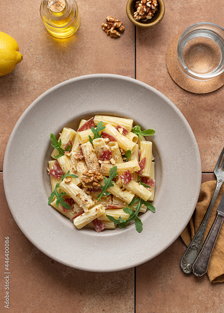 Dish of pasta with arugula, salami and walnuts Dish of pasta with arugula, salami and walnuts