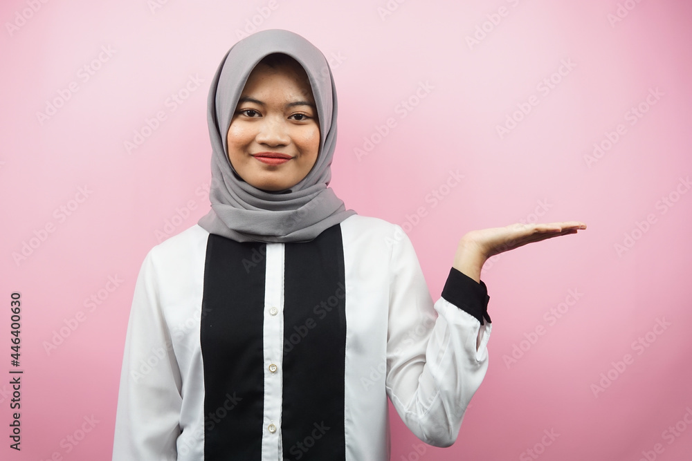 Beautiful young asian muslim woman with hands showing and presenting something in the direction of empty space, smiling confidently, excitedly, facing the camera, isolated on pink background Beautiful young asian muslim woman with hands showing and presenting something in the direction of empty space, smiling confidently, excitedly, facing the camera, isolated on pink background